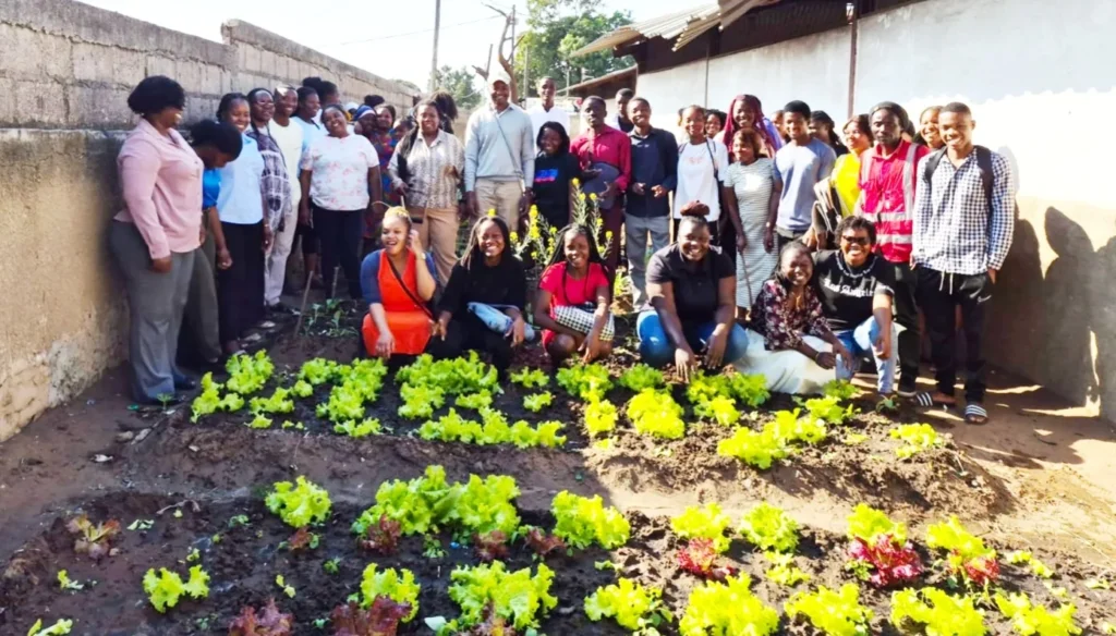 Group of young people beside the lettuce beds of a horticulture project